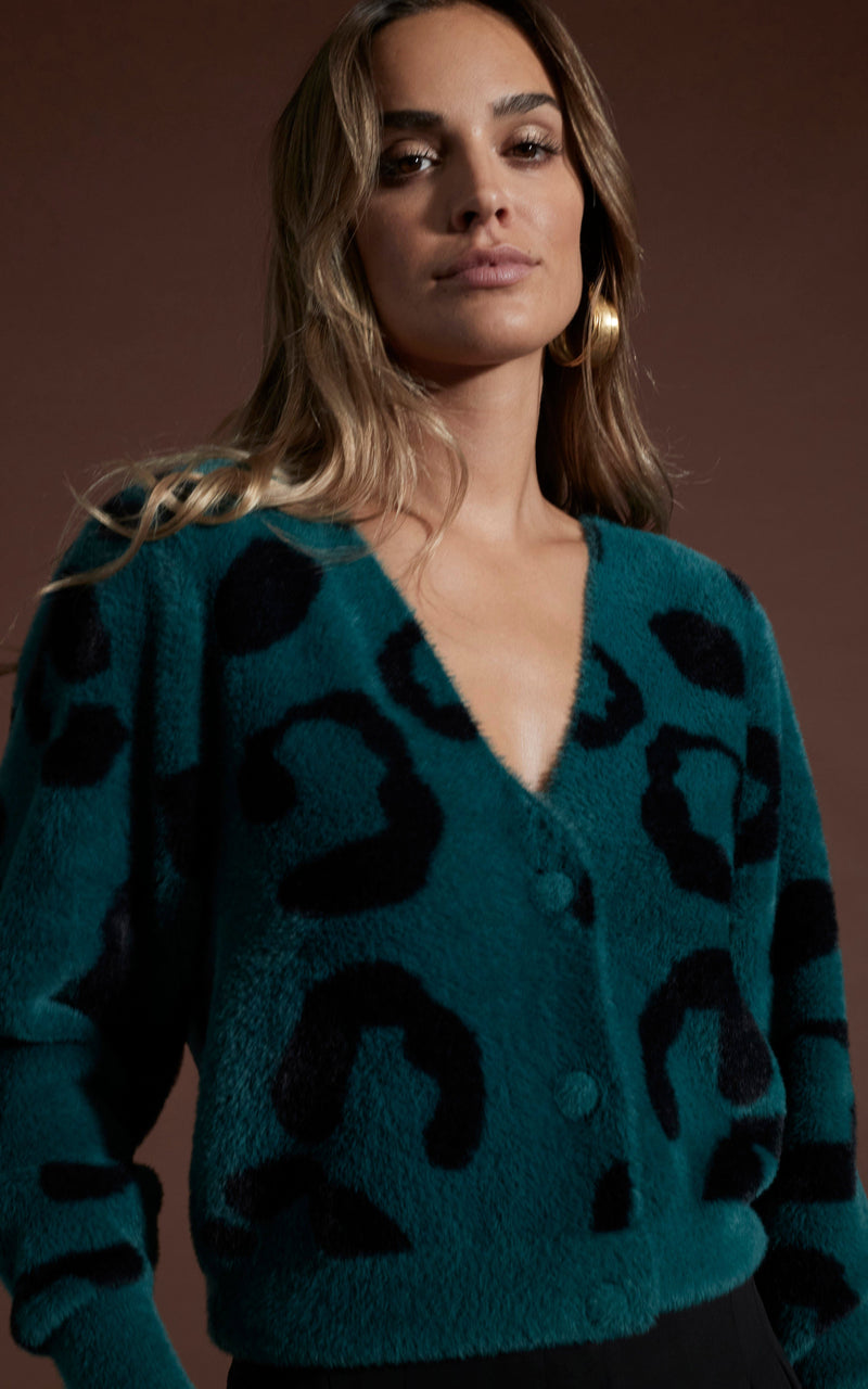 Close up of dancing leopard model standing facing the camera wearing Bambino cardigan in black on forest green leopard 