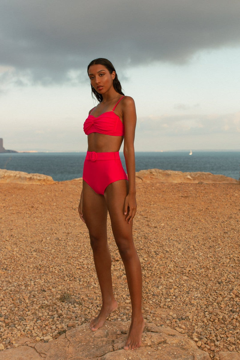 Dancing Leopard model faces forward and stands on beach wearing HALO Juniper bikini brief and Lalita bikini top in pink