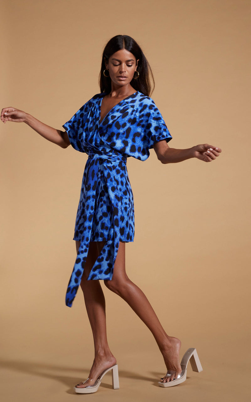 Dancing Leopard model wearing Kansas Mini Wrap Dress in Bright Blue Leopard posed side on with arms out
