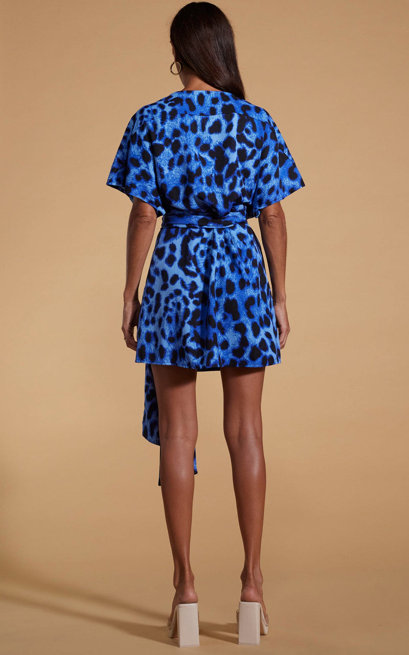 Dancing Leopard model wearing Kansas Mini Wrap Dress in Bright Blue Leopard facing away to show back of dress